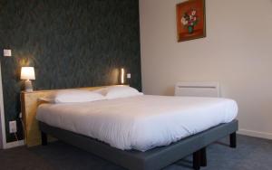 a bedroom with a large bed with white sheets at Logis Hotel De La Poste in Saint-Sauves- dʼAuvergne