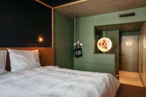 a bedroom with a white bed and a green wall at Superbude Wien Prater in Vienna