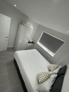 a bedroom with a bed with two pillows and a window at London Dagenham Apartments in Dagenham