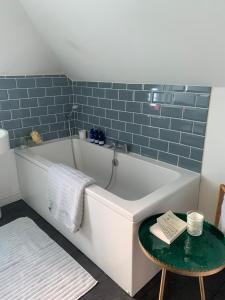a bath tub in a bathroom with blue tiles at Arran School House - Blackwaterfoot, Isle of Arran in Blackwaterfoot +18 photos
