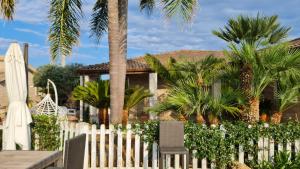 a white picket fence with a table and chairs and palm trees at Dependance Oscar in Carrozziere