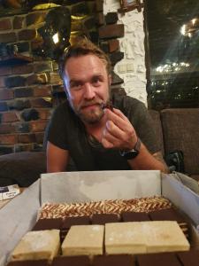 a man smoking a pipe next to a box of food at Vikendica Blidinje Čarobna kuća in Tomislavgrad +11 photos