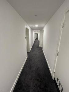 an empty hallway with white walls and black carpet at London Dagenham Apartments in Dagenham