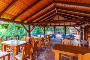 a restaurant with wooden tables and chairs and a roof at Villa Elena SPA & Resort in Bukovel