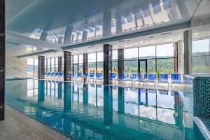 duży basen z niebieskimi krzesłami w budynku w obiekcie Villa Elena SPA & Resort w mieście Bukowel