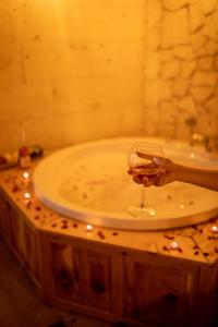 a person holding a wine glass in front of a sink at Pome Granate Cave Hotel in Nevşehir