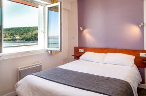 a bedroom with a bed and a large window at Hôtel & Restaurant de la Plage in Crozon