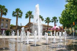 einen Brunnen in einem Park mit Palmen im Hintergrund in der Unterkunft L'appART'en ciel. Climatisé entre mer et canal in Villeneuve-lès-Béziers