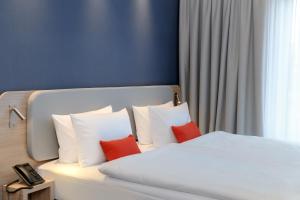 ein Schlafzimmer mit einem Bett mit zwei roten Kissen in der Unterkunft Holiday Inn Express Göttingen by IHG in Göttingen + 36 Fotos