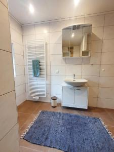a bathroom with a sink and a mirror and a rug at Ferienwohnung Sonnenblick in Edersee