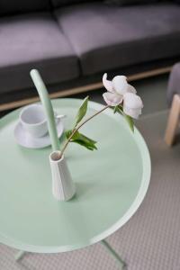 einen weißen Tisch mit einer Vase mit einer Blume darauf in der Unterkunft KOSI am Meer ACHT in Ostseebad Koserow