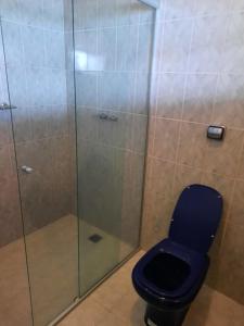 a bathroom with a blue toilet and a glass shower at Casa de Temporada Ponta Grossa - Paraty in Paraty