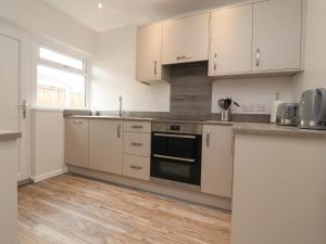 een keuken met witte kasten en een fornuis met oven bij Kings Walk in Cleveleys