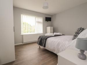 a white bedroom with a bed and a window at Kings Walk in Cleveleys