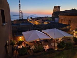 a rooftop patio with tables and umbrellas at night at Hotel Elimo in Erice