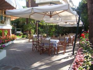 patio con tavoli e sedie sotto ombrellone di Hotel Escorial a Cervia