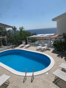 a large blue swimming pool with chairs and tables at Miriasol Bed and Breakfast in Capo Vaticano