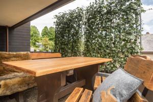 einen Holztisch und Stühle auf einer Terrasse mit einem Brunnen in der Unterkunft Heimelig im Hirschen App 117 in Schönwald