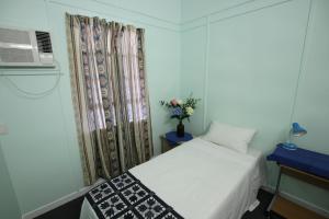 a small bedroom with a white bed and a window at Cairns Sunshine Lodge in Cairns North