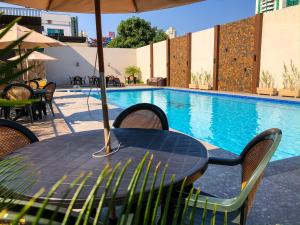 a table with chairs and an umbrella next to a swimming pool at Hotel Real in Foz do Iguaçu