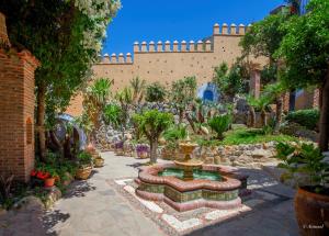 a garden with a fountain in front of a building at Dar Echchaouen Maison d'Hôtes & Riad in Chefchaouen