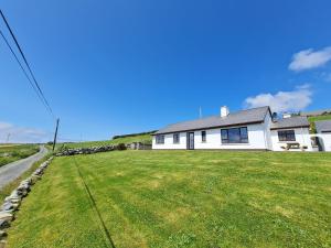 a white house with a large yard in front of it at Sea View Cottage, Errislannan in Ballyconneely