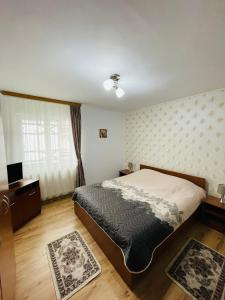 a bedroom with a bed and a window and two rugs at Apartament Bușteni in Buşteni