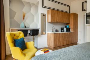 a bedroom with a yellow chair and a kitchen at Theatre Boutique Apartments - Stylish - Walk Everywhere in Kyiv