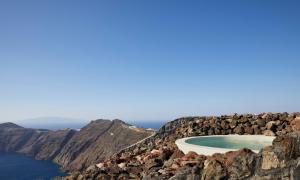 una piscina junto a una montaña con rocas en White Pearl Cavalieri en Imerovigli