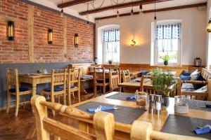 a restaurant with wooden tables and chairs and a brick wall at Hotel Kornblume in Haundorf