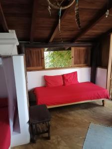 un letto rosso in una stanza con finestra di Castillo Oasis a Zipolite