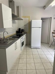 a kitchen with white cabinets and a white refrigerator at Le Patio Cathare in Carcassonne