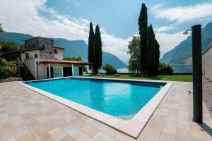a swimming pool in front of a house with mountains at Villa Onedo in Abbadia Lariana