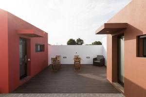 un patio con sillas, mesas y una pared blanca en As Casas da Margarida, en Ribeira Grande