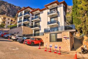a building with cars parked in a parking lot at Happy Kaş Apart in Kaş