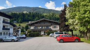 a red car parked in a parking lot in front of a house at Gästehaus Bräuer in Neukirchen am Großvenediger