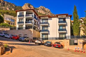 a building with cars parked in a parking lot at Happy Kaş Apart in Kaş