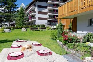 a table with plates and glasses in a yard at Naco Aparthotel by Arca Spa in Zermatt