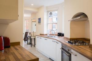 uma cozinha com armários brancos e uma bancada em 24 Molyneux Street em Londres