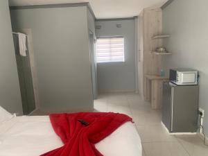 a bedroom with a bed with a red blanket on it at Waterfall View Lodge in Midrand