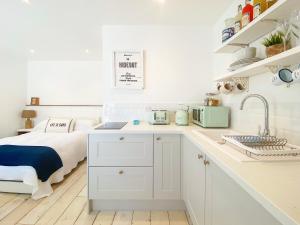 eine weiße Küche mit einem Bett und einem Waschbecken in der Unterkunft The Hideout in Chichester