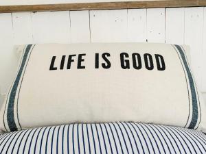 a pillow with the words life is good on a bed at The Hideout in Chichester