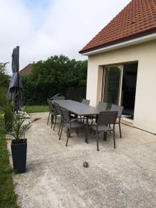einen Tisch mit Stühlen und einem Sonnenschirm auf einer Terrasse in der Unterkunft VENT DE FOLIE in Le Crotoy