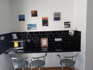 a black tiled wall with three bar stools at Dingle Wheelhouse in Dingle
