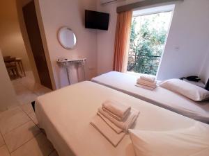 a bedroom with two beds and a window with towels at Anthemio in Loutraki