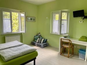 a green bedroom with a bed and a desk and windows at Impronte Nel Bosco in Calice al Cornoviglio