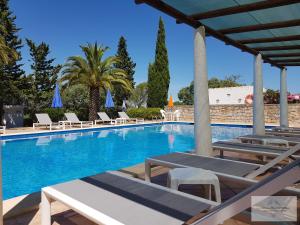 a large swimming pool with lounge chairs and umbrellas at Monte-Bougainvillea in Faro