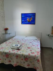クイアバにあるSuite 03 - Independente, privativa e aconcheganteの花の咲く毛布と壁に絵画が飾られたベッドルーム1室が備わります。