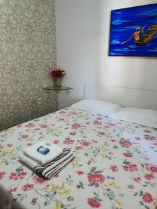 ein Bett mit einer Blumenbettdecke und Handtüchern darauf in der Unterkunft Suite 03 - Independente, privativa e aconchegante in Cuiabá