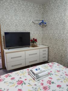 ein Schlafzimmer mit einem Bett und einem TV auf einer Kommode in der Unterkunft Suite 03 - Independente, privativa e aconchegante in Cuiabá